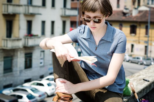 young beautiful hipster woman reading book in the city