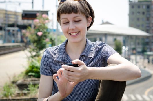 young beautiful hipster woman typing message on the phone in the city