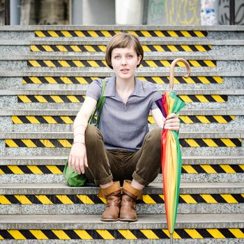 young beautiful hipster woman sitting on the stairs in the city