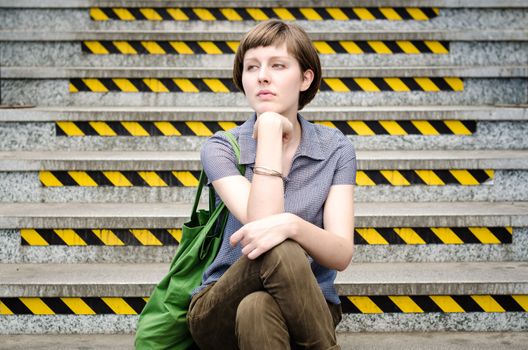 young beautiful hipster woman sitting on the stairs in the city