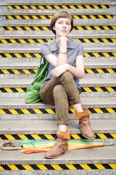 young beautiful hipster woman sitting on the stairs in the city