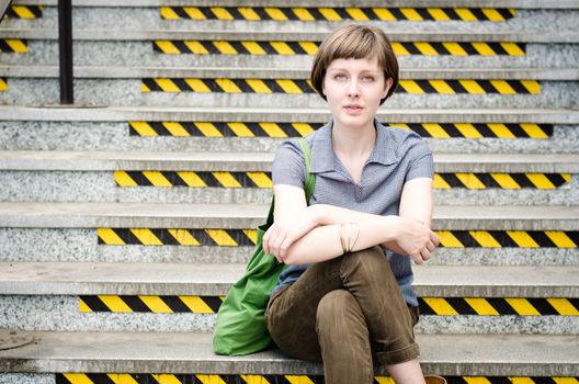 young beautiful hipster woman sitting on the stairs in the city