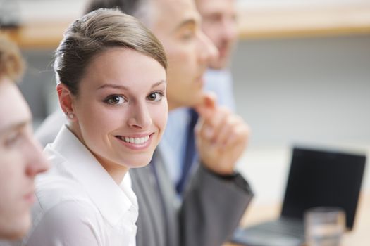 Portrait of a pretty young businesswoman sitting at a business meeting with colleagues