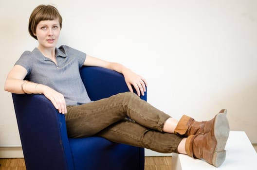 young beautiful hipster woman sitting in the armchair relaxing at home