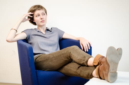 young beautiful hipster woman sitting in the armchair relaxing at home