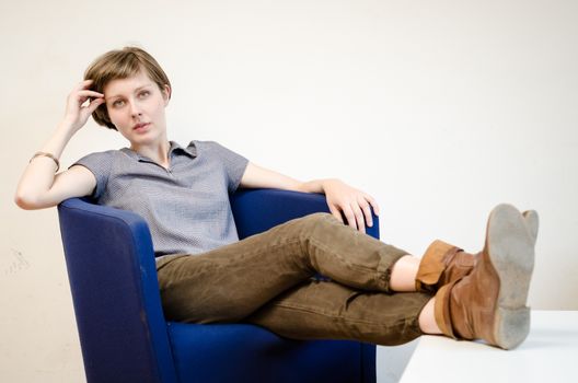 young beautiful hipster woman sitting in the armchair relaxing at home