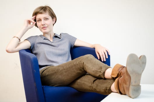 young beautiful hipster woman sitting in the armchair relaxing at home