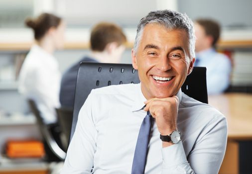 Mature businessman with meeting in the background