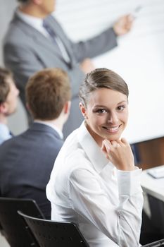 Portrait of a pretty young businesswoman smiling in a meeting with her colleagues in background