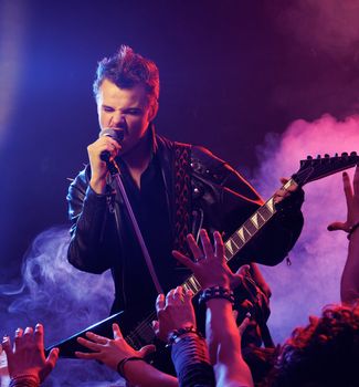 Guitarist singing on stage at a rock concert for his adoring fans