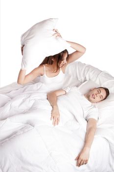 Frustrated wife trying to stop husband from snoring with pillow in bed, isolated.