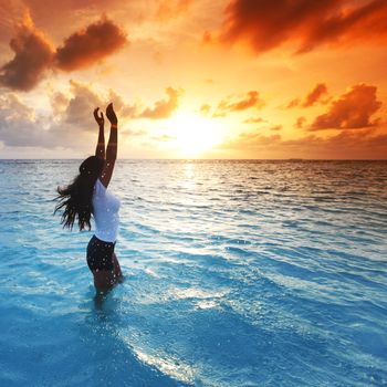 Beautiful woman in sea enjoying colorful sunset