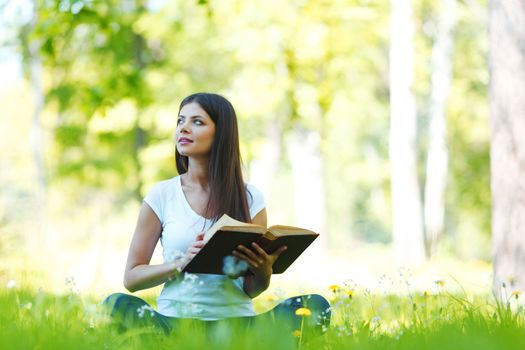 Woman reading book in park outdoors