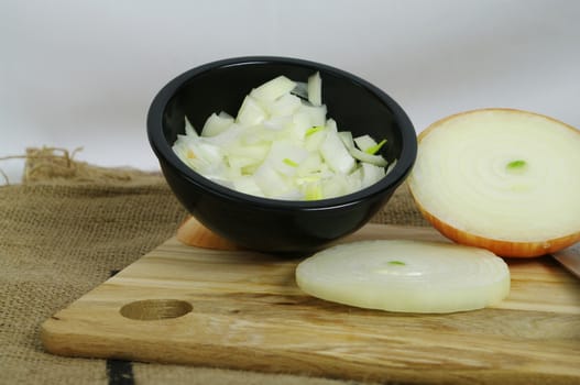 Raw Onion Diced in a black bowl on a bamboo board