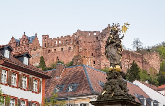Statue of Madonna Mary and Jesus in town square of old town city of Heidelberg Germany with castle walls background
