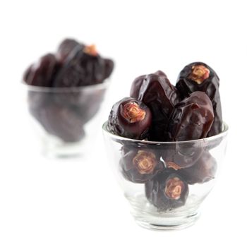 Dates fruit. Pile of dried date fruits in glass isolated on white background.