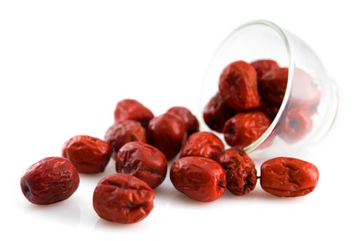 Dried red date spill from a glass. Chinese jujube. Traditional herbal medicine isolated on white background.