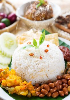 Nasi lemak traditional malaysia spicy rice dish, fresh cooked with hot steam. Served with belacan, ikan bilis, acar, peanuts and cucumber. Decoration setup, malaysian cuisine.