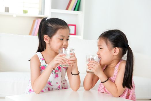 Children drinking milk. Asian family at home. Beautiful sister drinks milk together.