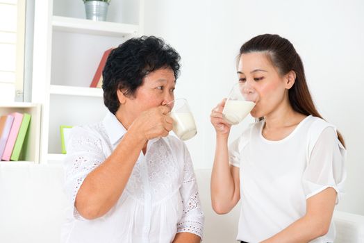 Drinking milk. Happy Asian family drinking milk at home. Beautiful senior mother and adult daughter, healthcare concept.