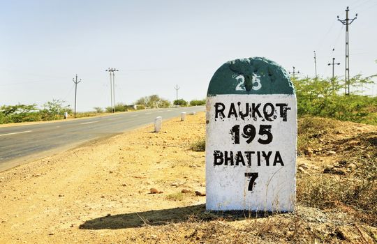 Horizontal color landscape of the 195 kilometers to Rajkot milestone on the Gujarat State Highway which runs through barren land in India