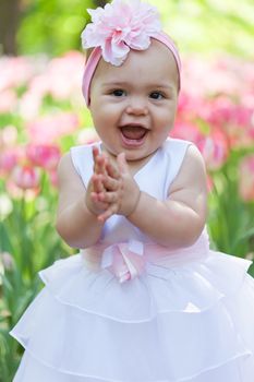 little girl in an elegant dress to stand near blossoming tulips