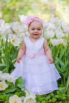 little girl in an elegant dress to stand near blossoming tulips