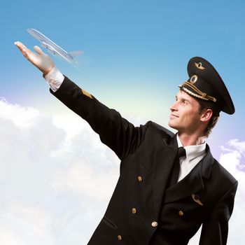 pilot in the form of extending a hand to a flying airplane on the background of sky with clouds