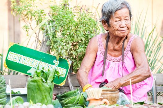 SUKHOTHAI, THAILAND - MAY 4: Unidentified mature woman is selling Thai traditional snack on May 4, 2013 at Rim Yom 2437 night market, Sukhothai, Thailand.