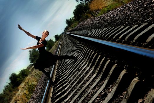 Ballet dancer on the railway in dynamic pose