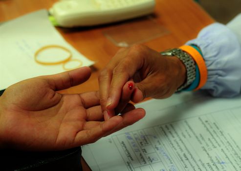 Nurse collects blood specimen from a finger