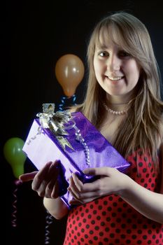 smiling girl with a gift box on a dark background with balloons