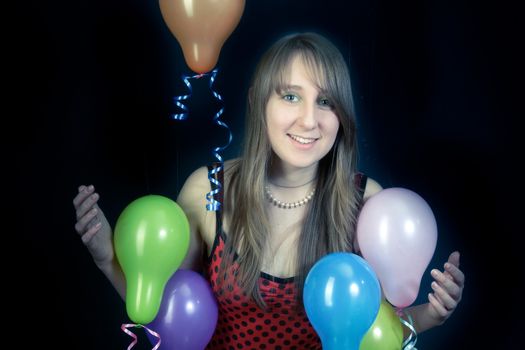 A smiling girl with colorful balloons on a dark background