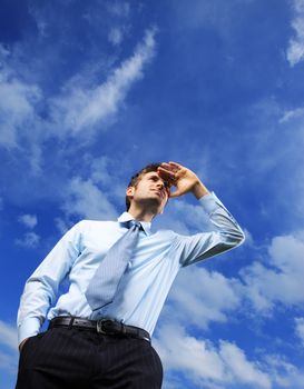 Young Business man looking away against blue sky