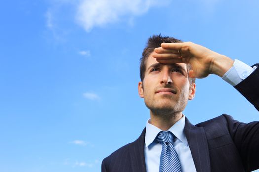 Young Business man looking away against blue sky