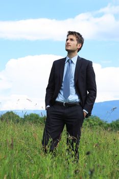 Portrait of a young business man walking in a meadow