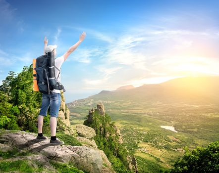 Tourist with backpack enjoy valley view from top of a mountain