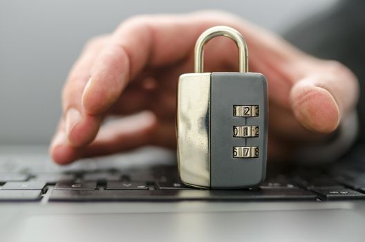 Male hand stealing padlock off computer keyboard.