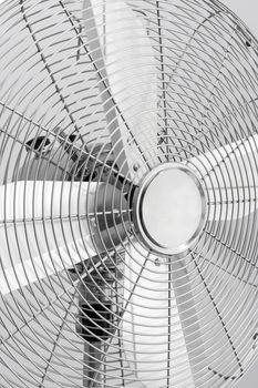 Close-up of a modern metal electric fan with shiny blades.