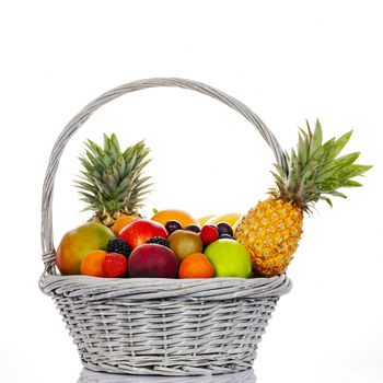 Composition with assorted fruits in wicker basket on white background