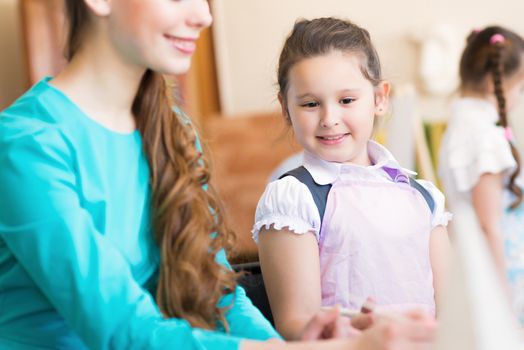 girl in the school, near the teacher and other children