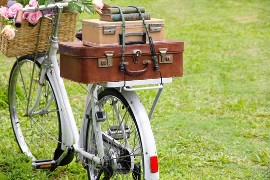 Vintage bicycle on the field with a basket of flowers and bag