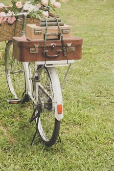 Vintage bicycle on the field with a basket of flowers and bag