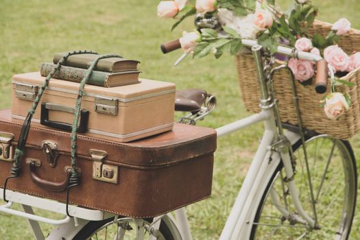 Vintage bicycle on the field with a basket of flowers and bag