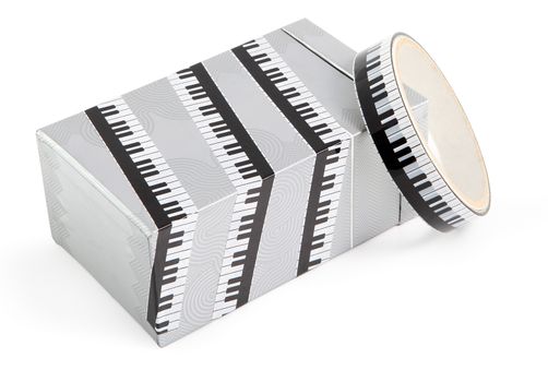 A box wrapped in decorative adhesive packaging tape with print piano. Adhesive tape with a black and white print, used for packing gifts.