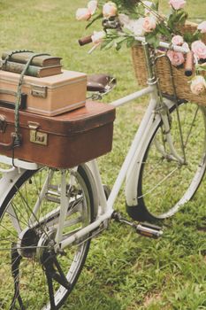 Vintage bicycle on the field with a basket of flowers and bag