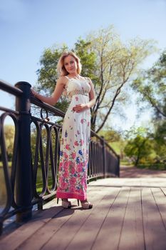 beautiful, young woman standing on the bridge, holding on to the fence