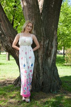 beautiful, young woman standing near the tree in the park