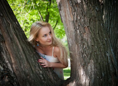 beautiful, young woman standing near the tree in the park