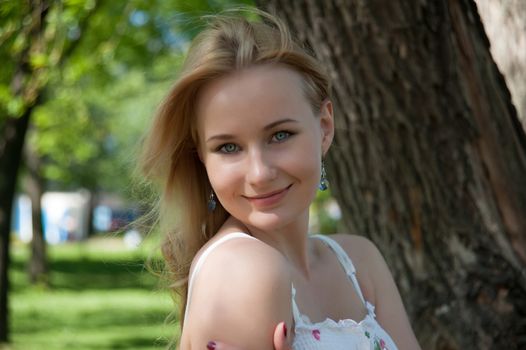 beautiful, young woman standing near the tree in the park